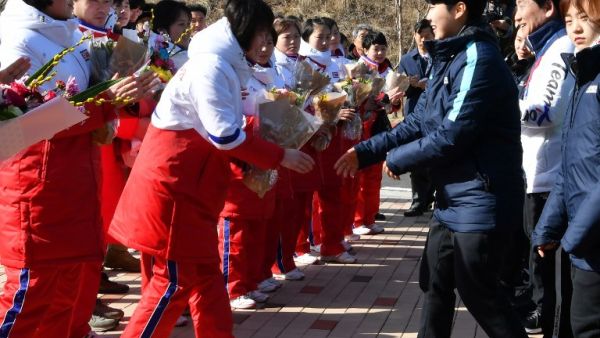 Members of North Korean women's ice hockey team (in white and red) are welcomed by members of the South Korean team (in blue) as they arrive at South Korea's national training centre in Jincheon on January 25, 2018. 
Song Kyung-Seok / POOL / AFP