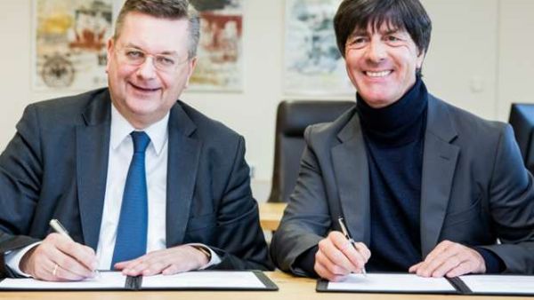 لوف (يمين) يوقع على عقد استمراره مع ألمانيا
