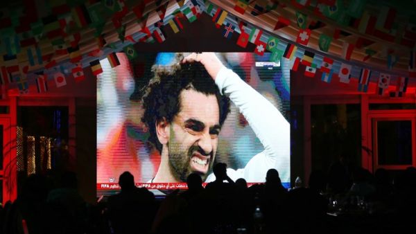 Egyptian striker Mohamed Salah's face is seen on a screen as people watch the Russia 2018 World Cup Group A football match between Russia and Egypt on June 19, 2018 in Kuwait City.
Yasser Al-Zayyat / AFP