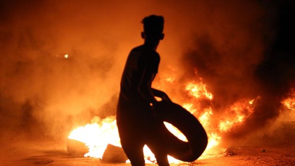 A resident of Basra holds up a tire outside the burning Iranian Consulate (AFP/FILE)