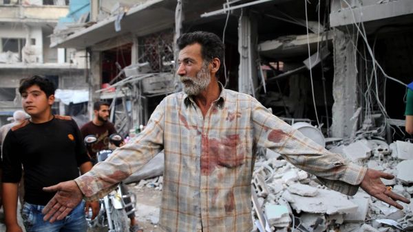 A Syrian man holds up his hands after Russian air strike in the district of Jisr Al-Shughur in the Idlib province (AFP/FILE)