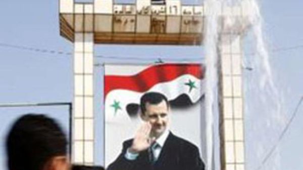 شبان يمرون امام صورة كبيرة لبشار الاسد في درعا