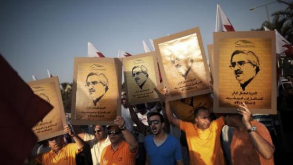 Demonstrators outside the Bahraini capital Manama hold up posters of jailed secular opposition leader Ibrahim Sharif who was released Friday after four years in prison.  (AFP/File)