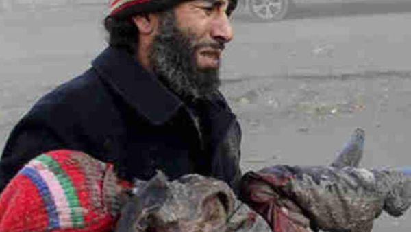 A Syrian man cries carrying the body of a child killed by a barrel bomb. [gendynamics]