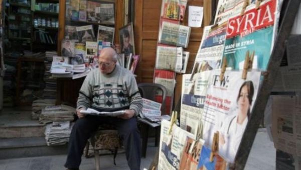 سوري يطالع الصحف امام محله في دمشق