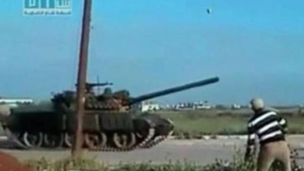 رجل يلقى حجرا على دبابة مارة في درعا يوم الاثنين 
