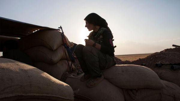 A fighter of the Kurdish of the Kurdish Women's Defense Units (YPJ) sits on sand bags as she holds a position on the front line in Syria. (Image credit: AFP) 