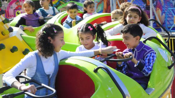 Syrian children ride on a merry-go-round as families celebrate the Muslim feast of Eid al-Adha. (Image credit: AFP)