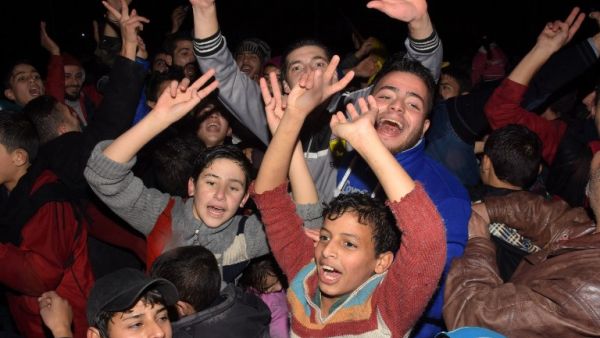 Syrians celebrate on December 12, 2016 in the government-held Mogambo neighbourhood of the northern Syrian city of Aleppo, after rebel fighters retreated into a small pocket of their former bastion in the face of new army advances. (AFP/George Ourfalian)