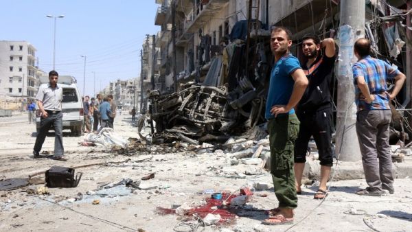 Syrians stand next to debris and bloodstains following bombardment by government forces on the Salhin district of the northern city of Aleppo on July 21, 2016. (AFP/Thaer Mohammed)