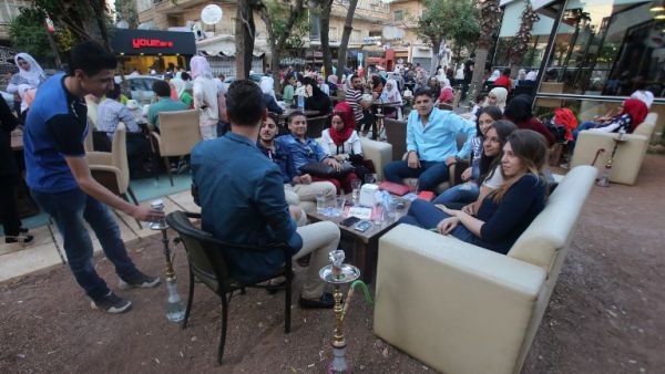 Syrian youths sit at a cafe in the government-held Mogambo neighbourhood of the northern Syrian city of Aleppo as they celebrate the Eid al-Adha Muslim holiday on September 13, 2016, a day after a fragile ceasefire was brokered. (AFP/Youssef Karwashan)