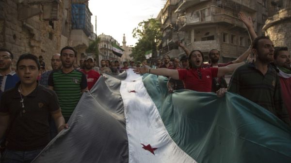 Syrians carry a giant pre-Baath Syrian flag as they shout slogans during an anti-regime protest in the rebel-held Bustan al-Qasr district in eastern Aleppo on May 5, 2016. (AFP/Karam al-Masri)