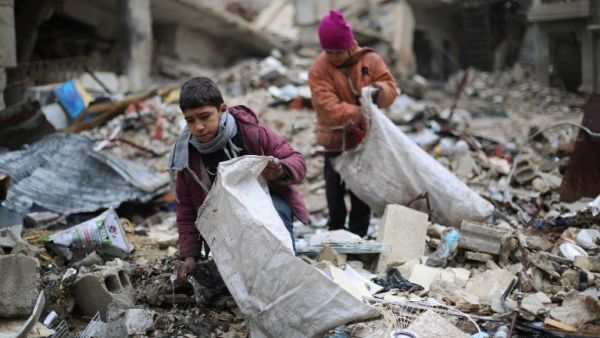 Syrian youths collect wood from rubble to be used for heating and cooking, on December 27, 2016, in the Damascus rebel-held eastern suburb of Zamalka. (Amer al-Mohibany)