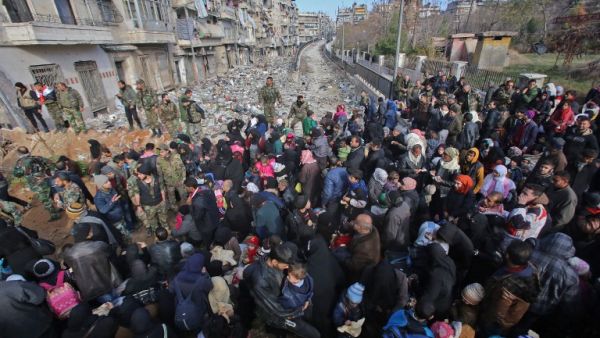 Syrian residents fleeing the violence gather at a checkpoint, manned by pro-government forces, in the Maysaloun neighborhood of the northern city of Aleppo on December 8, 2016. (AFP/Youssef Karwashan)