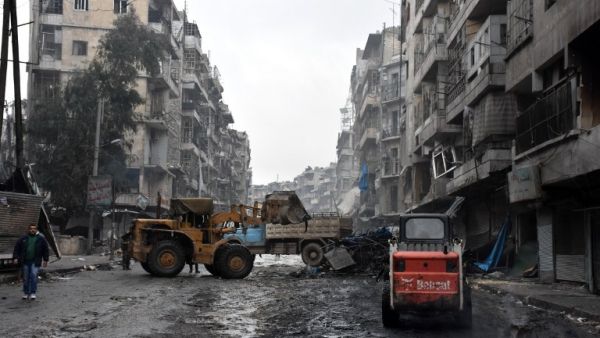 A tractor removes rubble as the Syrian government starts to clean up areas formerly held by opposition forces in the northern city of Aleppo on December 27, 2016, in the Shaar district. (AFP/George Ourfalian)