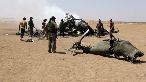 A picture taken on August 1, 2016 shows Syrian rebels gathering around the wreckage of a Russian Mi-8 military transport helicopter after it was shot down in Idlib province. (AFP/Mohamed al-Bakour)