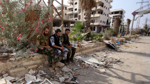 Syrian army soldiers gather in a street in the government-controlled part of the besieged town of Daraya on August 26, 2016, as thousands of rebel fighters and civilians prepared to evacuate under an accord struck a day earlier. (AFP/Youssef Karwashan)