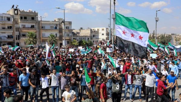 Syrians from Idlib and its surrounding towns wave the flag of the opposition and chant slogans as they gather for an anti-government demonstration in a main square on September 14, 2018. (OMAR HAJ KADOUR / AFP)

