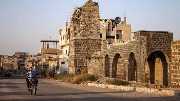 A Syrian man rides a motorcycle while carrying a gas cylinder as he drives past the Omari mosque in a rebel-held area in the southern Syrian city of Daraa on October 2, 2018. (Mohamad ABAZEED / AFP)