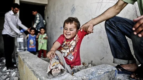A Syrian man holds his infant in front of a disused house. (AFP)