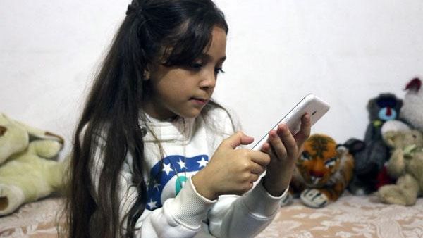 Seven-year-old Bana Alabed checks her Twitter account on her mother's smartphone. [AFP]