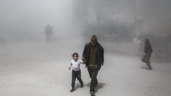 A Syrian man and girl flee following a reported government air strike on the rebel-controlled town of Hamouria. (AFP/ File Photo)