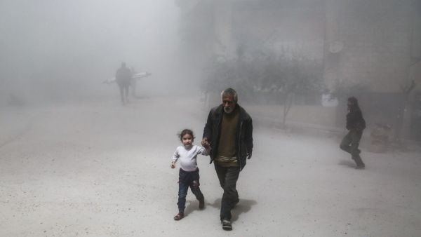 A Syrian man and girl flee following a reported government air strike on the rebel-controlled town of Hamouria. (AFP/ File Photo)