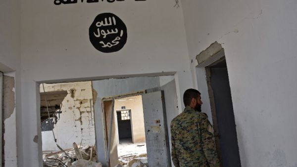 A Syrian government forces fighter walking under Islamic State (IS) group graffiti in a house in Deir Hafer on the eastern outskirts of Aleppo on March 30, 2017, after they took control of the village. (George Ourfalian/AFP)