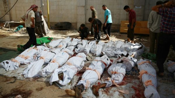 Syrians and emergency personnel gather around dead bodies wrapped in shrouds following air strikes in Douma. (AFP/ File)