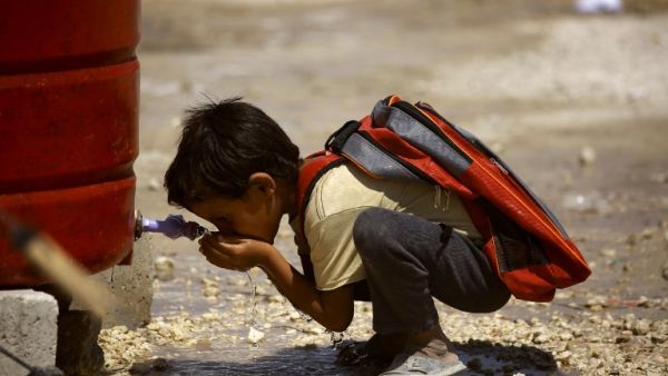 A displaced child from the Islamic State (IS) group's Syrian stronghold of Raqa, drinks water. (AFP)