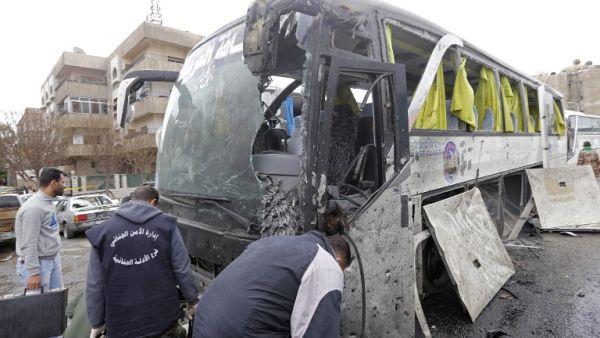 Syrian forensics examine a damaged bus at the scene of a bombing following twin attacks targeting Shiite pilgrims in Damascus' Old City on March 11, 2017. (AFP/Louai Beshara)