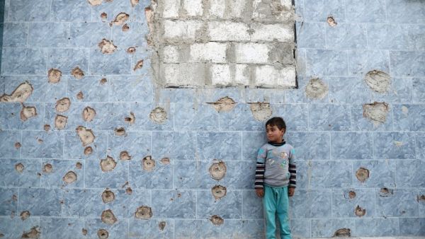 A Syrian boy stands against a bullet-riddled wall in the rebel-held town of Douma, on the eastern outskirts of the Syrian capital Damascus, on April 24, 2017. (AFP/Abd Doumany)