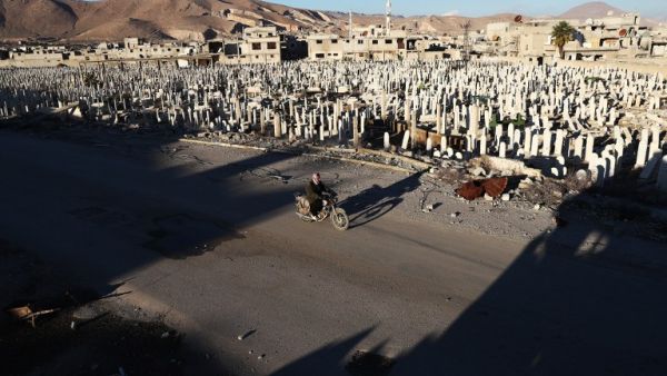 A Syrian man rides a motorbike past a cemetery in the rebel-held town of Douma, on the eastern outskirts of Damascus, on January 3, 2017. (AFP/Abd Doumany)
