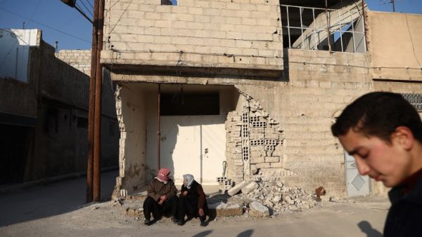 A Syrian boy walks past two men chatting in the rebel-held town of Douma, on the eastern outskirts of the capital Damascus, on January 7, 2017. (AFP/Abd Doumany)