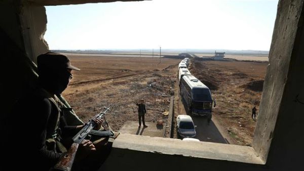 A militant watches as a convoy of buses gets ready to enter the towns of Foua and Kefraya to evacuate their residents on July 18, 2018. (AFP/ File)