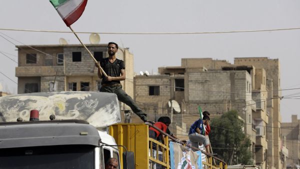 A Syrian man holds the Iranian flag as a convoy carrying aid provided by Iran arrives in the eastern city of Deir Ezzor. (LOUAI BESHARA/ AFP)