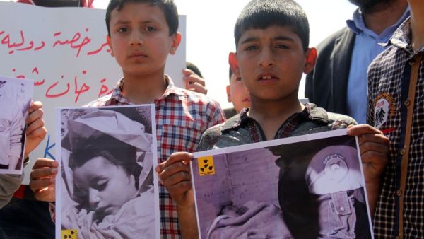 Syrian residents of Khan Sheikhoun hold placards and pictures on April 7, 2017 during a protest condemning a suspected chemical weapons attack on their town that killed at least 86 people, among them 30 children. (AFP/Omar Haj Kadour)