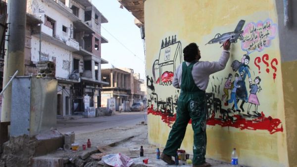 Syrian artist Aziz al-Asmar works on a mural depicting the war in Syria. (AFP/File)