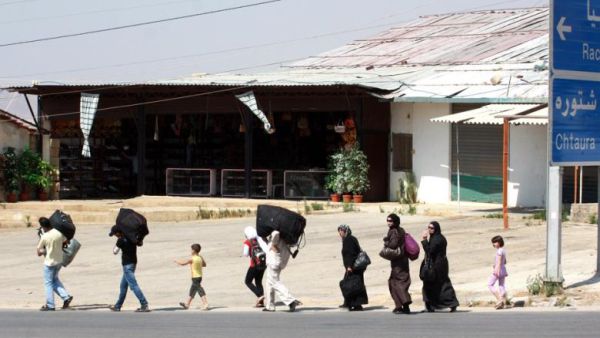 Carrying their luggage people walk close to the area of the Masnaa crossing between the eastern Lebanon and neighboring Syria on 19 July 2012. (AFP/File)