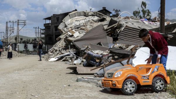 A child plays with a toy car in a street next to damaged buildings after heavy fightings between Turkish government troops and Kurdish fighters after the curfew in the southeastern Turkey Kurdish town of Yuksekova. (AFP/File)