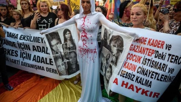A LGBT protester stands in front of a banner and "We want to live" written on her body on August 21, 2016 in Istanbul during a demonstration against the murder of transgender activist Hande Kader.. (AFP/Ozan Kose)