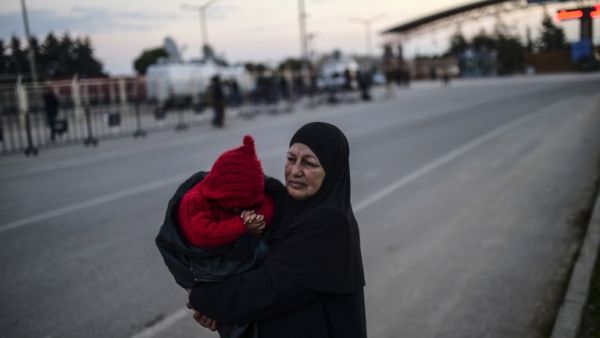 Syrian refugee Hatice Henidil hugs her grandson Usame while waiting for his parents still stuck on the Syrian side of the border, in front of the Oncupinar crossing in southern Turkey, on Feb. 10, 2016. (AFP/Bulent Kilic)