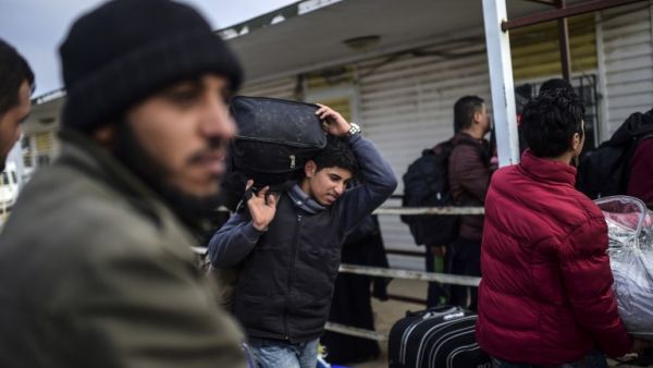 Syrian people wait in front of the Oncupinar crossing gate to go back to Syria, near the town of Kilis, in south-central Turkey, on February 11, 2016. (AFP/Bulent Kilic)