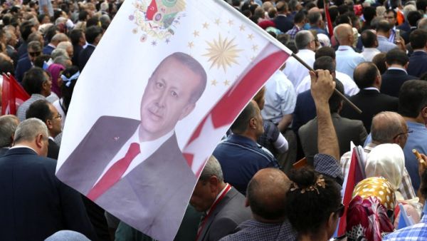 A man holds a flag with the portrait of Turkey President Recep Tayyip Erdogan as people gather during a meeting marking the 15th anniversary of the foundation of Justice and Development (AK) Party in Ankara, on August 14, 2016. (AFP/Adem Altan)