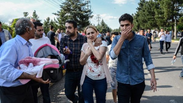 An injured woman, next to a man carrying her baby, walks near the site where a bomb explosed on May 10, 2016 in Diyarbakir. Three people were killed and 22 wounded in the attack. (AFP/Ilyas Akengen)