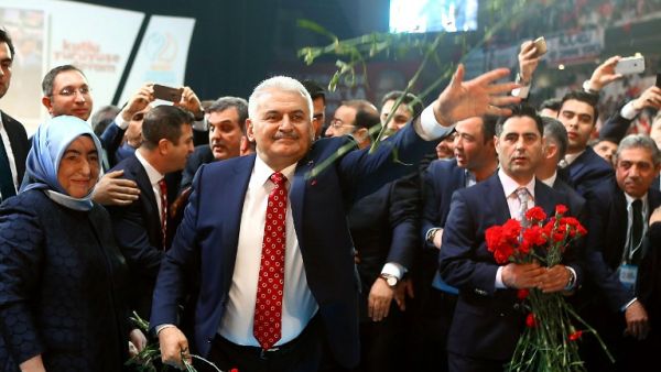 Turkey's Minister of Transport, Maritime and Communication and new chairman candidate for ruling AK Party Binali Yildirim throws red carnations to supporters as he arrives for the second extraordinary congress in Ankara, on May 22, 2016. (AFP/Adem Altan)