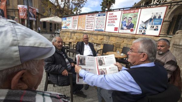People sit next to campaign posters for parliamentary elections at a cafe in the northern part of Nicosia in the Turkish Republic of Northern Cyprus on January 3, 2018. (AFP/ File)
