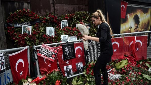 A woman lays flowers by a makeshift memorial in front of the Reina nightclub in Istanbul on January 17, 2017, a day after Turkish police arrested the suspected attacker. (AFP/Ozan Kose)