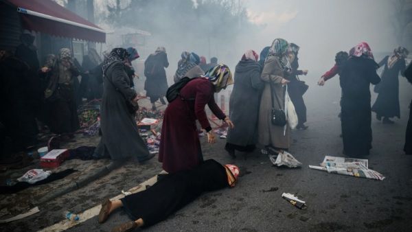 A woman helps a fallen friend as riot police launch tear gas at peaceful protesters outside Zaman in Istanbul. (AFP/Ozan Kose)