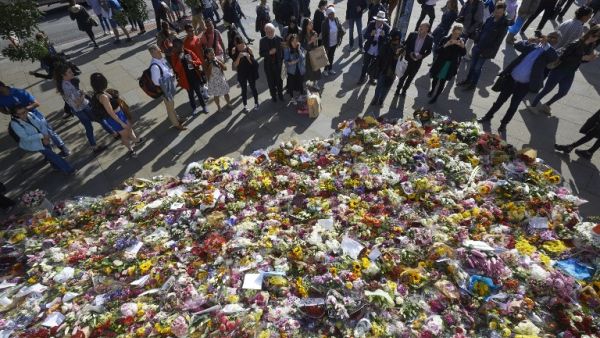 Pedestrians stop to look at floral tributes left by well-wishers on London bridge in London on June 9, 2017, following the June 3 terror attack that targeted members of the public on London Bridge and Borough Market (Niklas Halle'n/AFP)